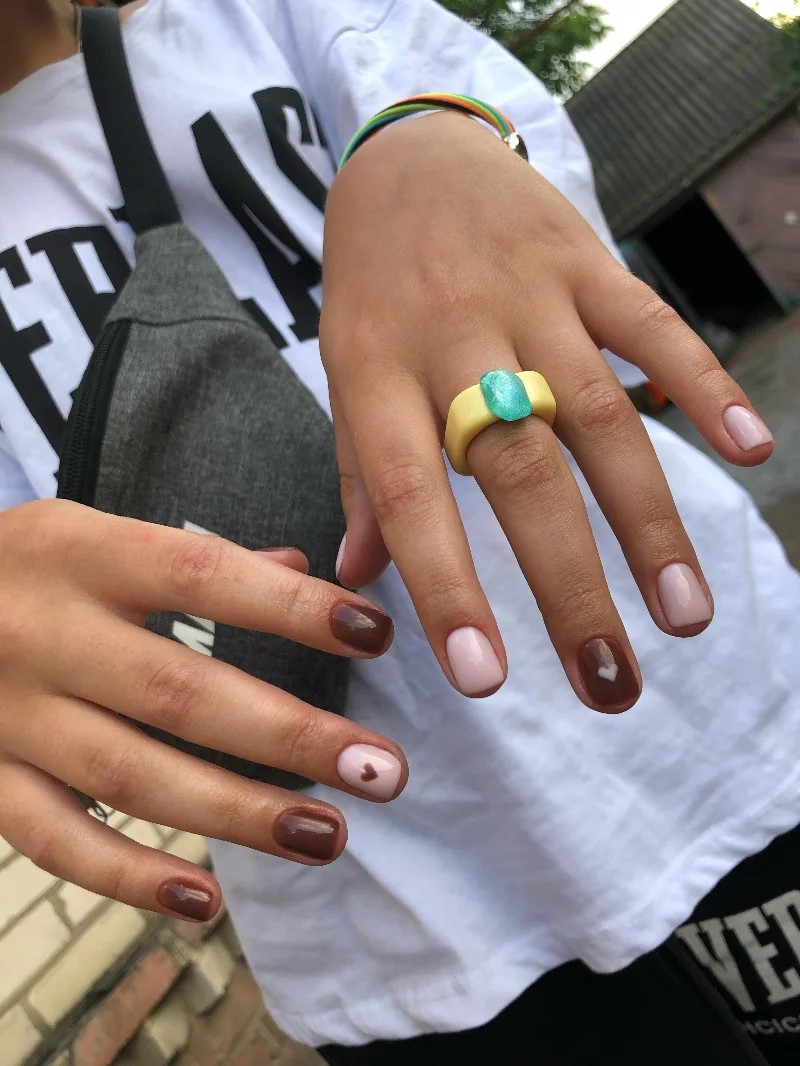 Vrouw in een wit T-shirt die buiten haar BIAB-manicure aan de camera laat zien
