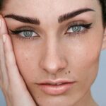 Close-up van het gezicht van een vrouw met microblading op haar wenkbrauwen en natuurlijke make-up, met donker haar dat is opgestoken