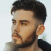 Man die buiten staat met donker haar en een taper fade kapsel met een getextureerde bovenkant