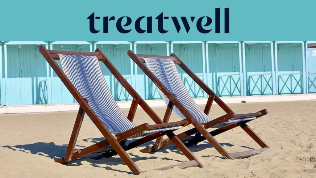 Twee gestreepte houten ligstoelen op het zand voor pastelblauwe strandhuisjes aan de kust van Versilia